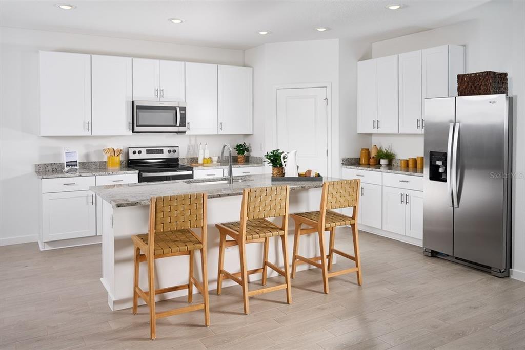 A modern kitchen features white cabinets, granite countertops, stainless steel appliances, and a central island — 76 ARARAT DRIVE, PALM COAST, FL