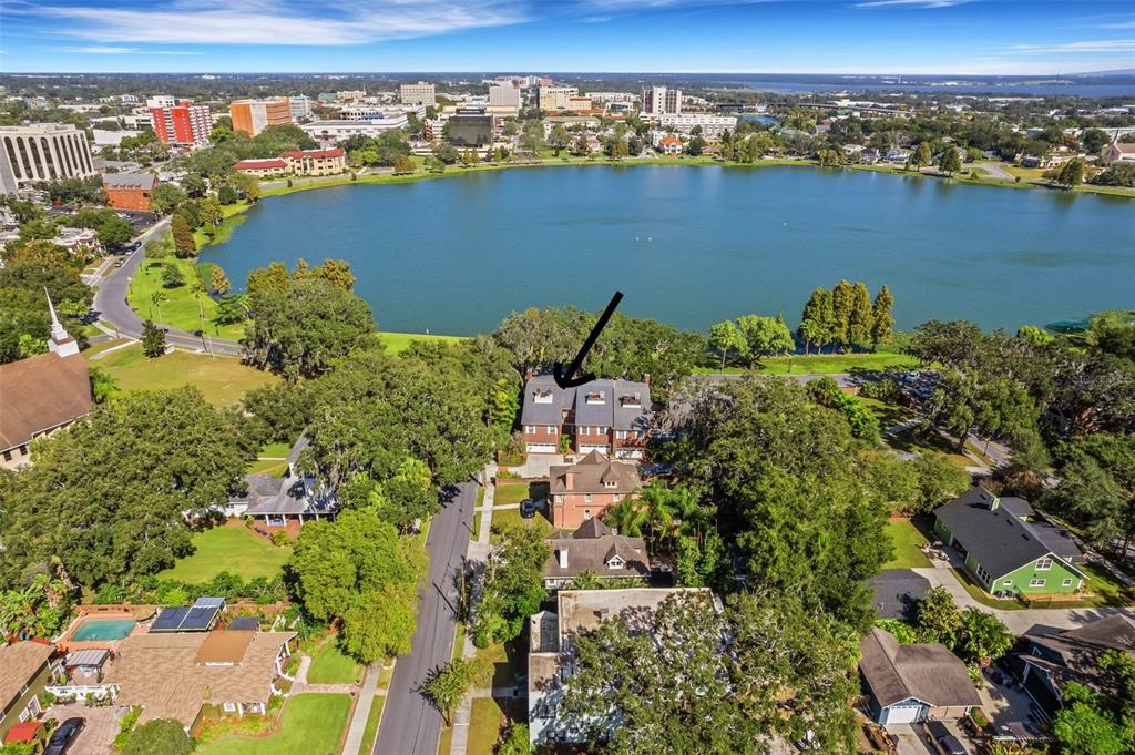 An aerial view shows a multi-story residential building near a lake in a city — 155 LAKE MORTON DRIVE UNIT 1, LAKELAND, FL