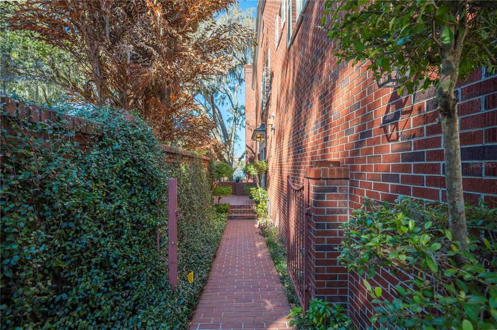A brick walkway leads along the side of a brick building past a vine-covered wall — 155 LAKE MORTON DRIVE UNIT 1, LAKELAND, FL