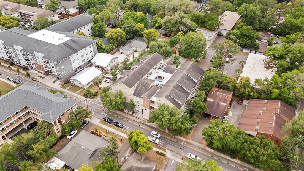 An aerial view shows a multi-story apartment complex surrounded by trees and paved parking lots — 1500 NW 4TH AVENUE UNIT 208, GAINESVILLE, FL