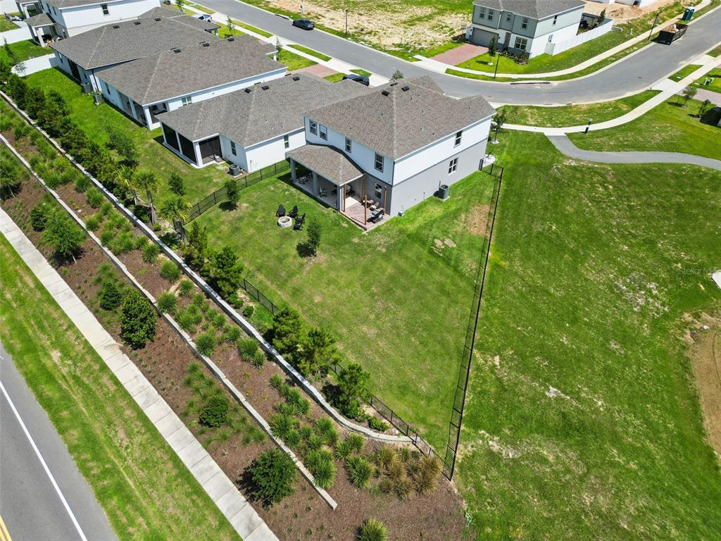 An aerial view shows a two-story house with a fenced backyard and tiered landscaping — 7114 ROLLING LEAF ROAD, GROVELAND, FL