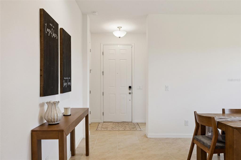 A white front door opens into a tiled entryway featuring a wooden console table — 7114 ROLLING LEAF ROAD, GROVELAND, FL