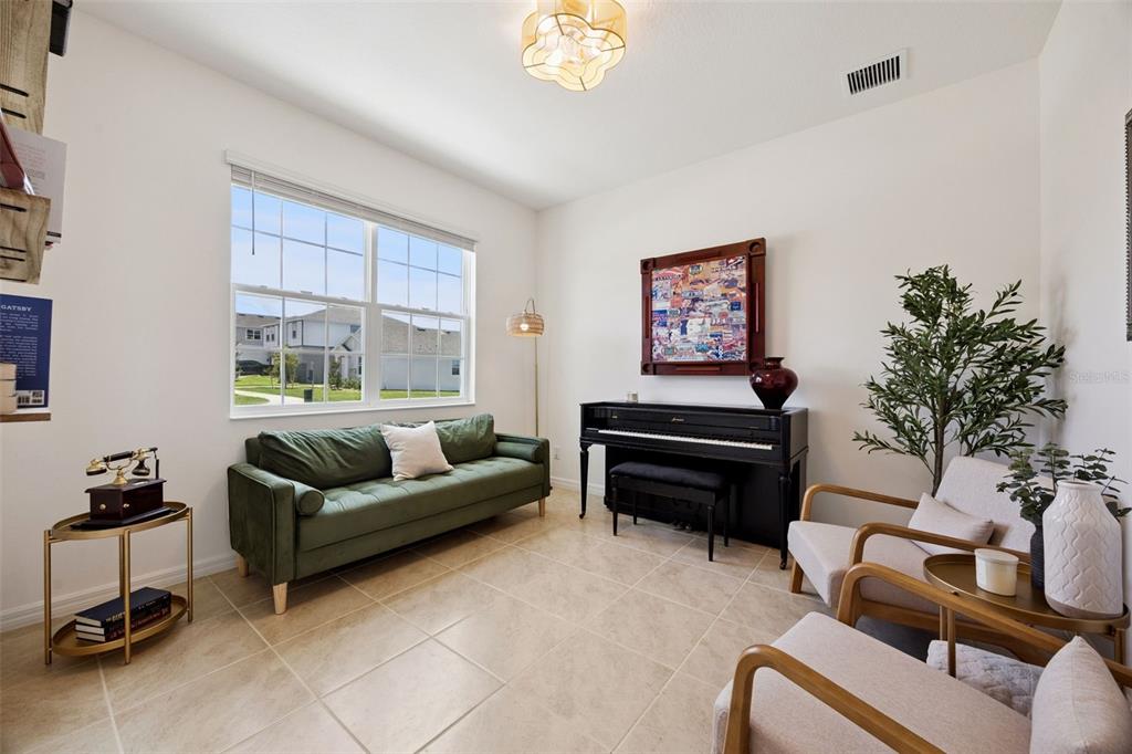 A living room features a green sofa, a black piano, and two armchairs on tile flooring — 7114 ROLLING LEAF ROAD, GROVELAND, FL
