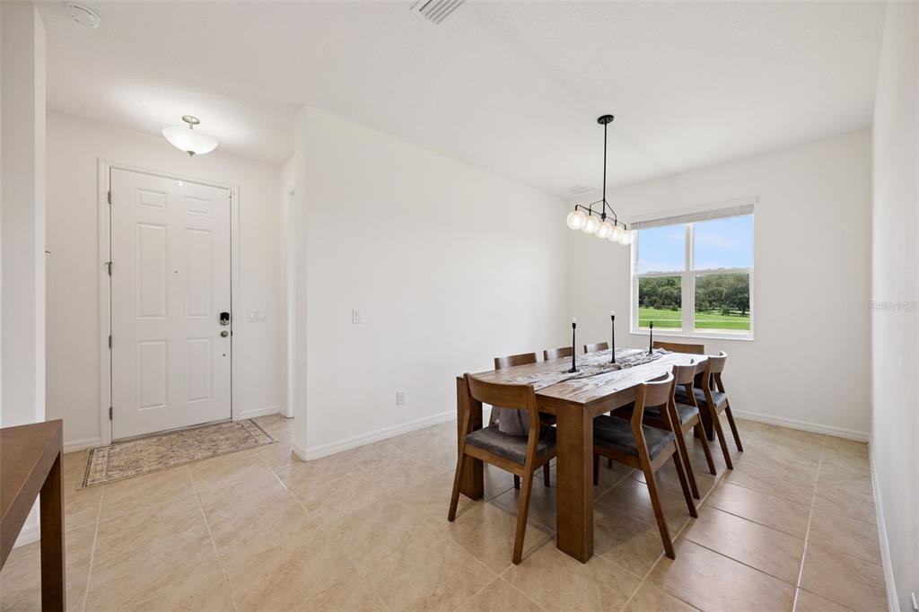 A dining room with tile floors, a wooden table, and a view of a grassy field — 7114 ROLLING LEAF ROAD, GROVELAND, FL