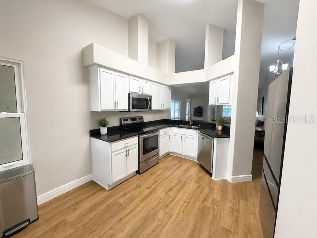 A kitchen features white cabinets, stainless steel appliances, and light wood-look flooring — 30913 BRIDGEGATE DRIVE, WESLEY CHAPEL, FL
