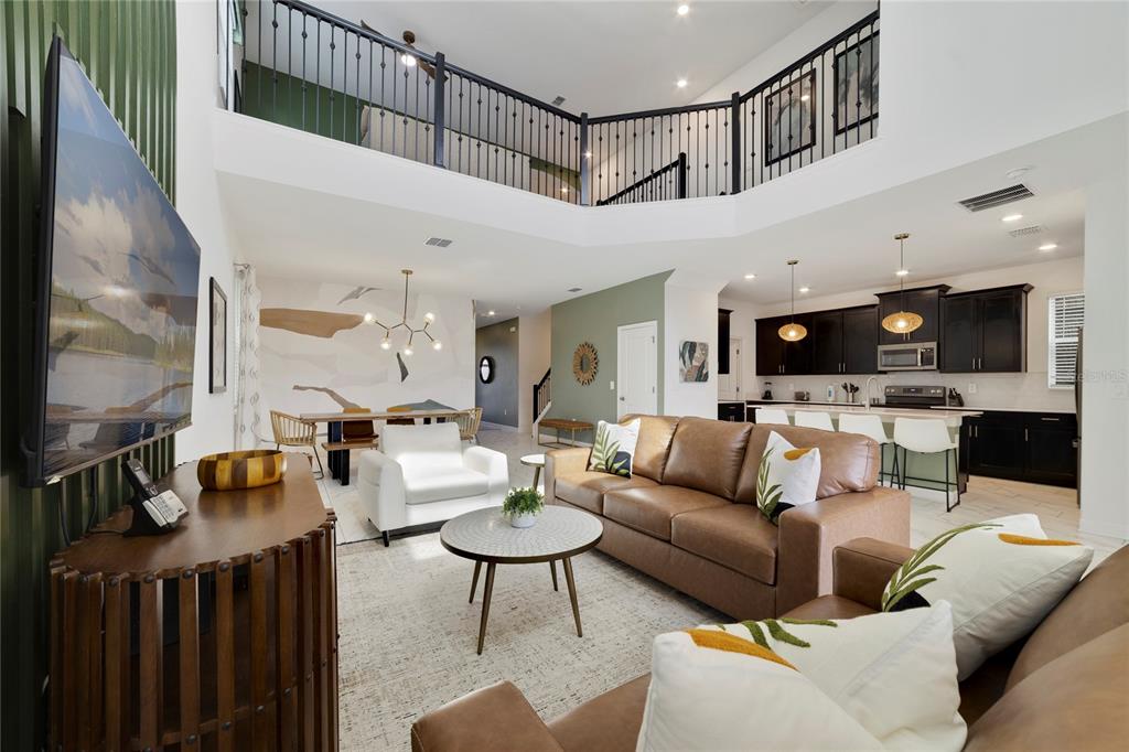 A living room with a brown sofa, white armchair, and an open kitchen with dark cabinets — 9199 SOMMERSET HILLS DRIVE, DAVENPORT, FL