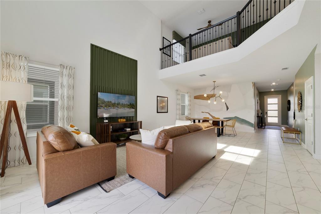 A living room with leather sofas, a green accent wall, and a lofted balcony above — 9199 SOMMERSET HILLS DRIVE, DAVENPORT, FL