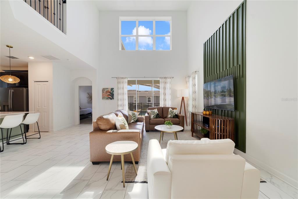 A bright living room features high ceilings, a green accent wall, and tiled flooring — 9199 SOMMERSET HILLS DRIVE, DAVENPORT, FL
