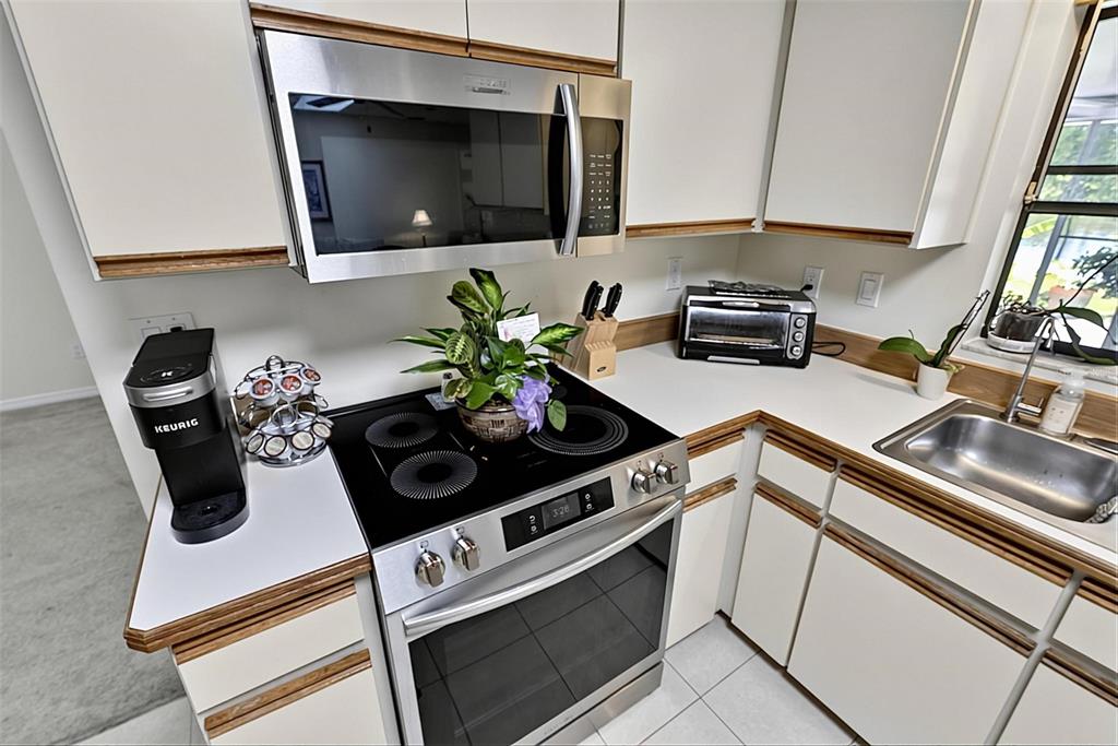 A kitchen features white cabinets, stainless steel appliances, a glass cooktop, and a double sink — 1408 ROYAL GROVE LANE, PORT ORANGE, FL