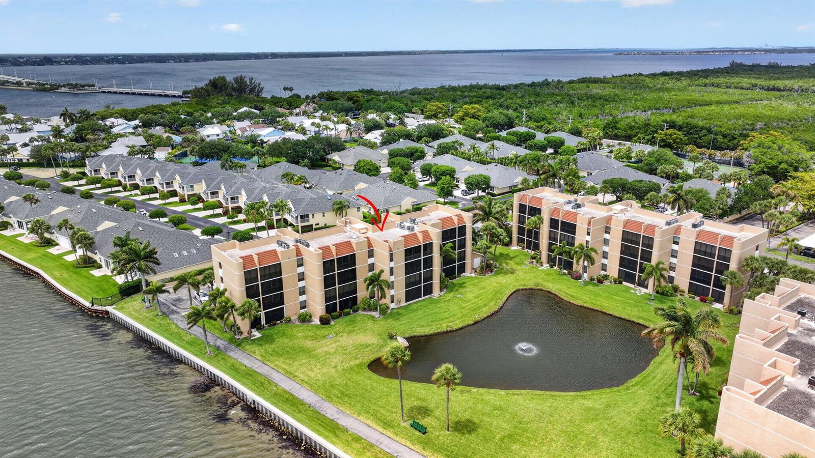 An aerial view shows multi-story apartment buildings situated next to a pond and a bay — 3382 NE Causeway Boulevard # 403, Jensen Beach FL 34957, JENSEN BEACH, FL