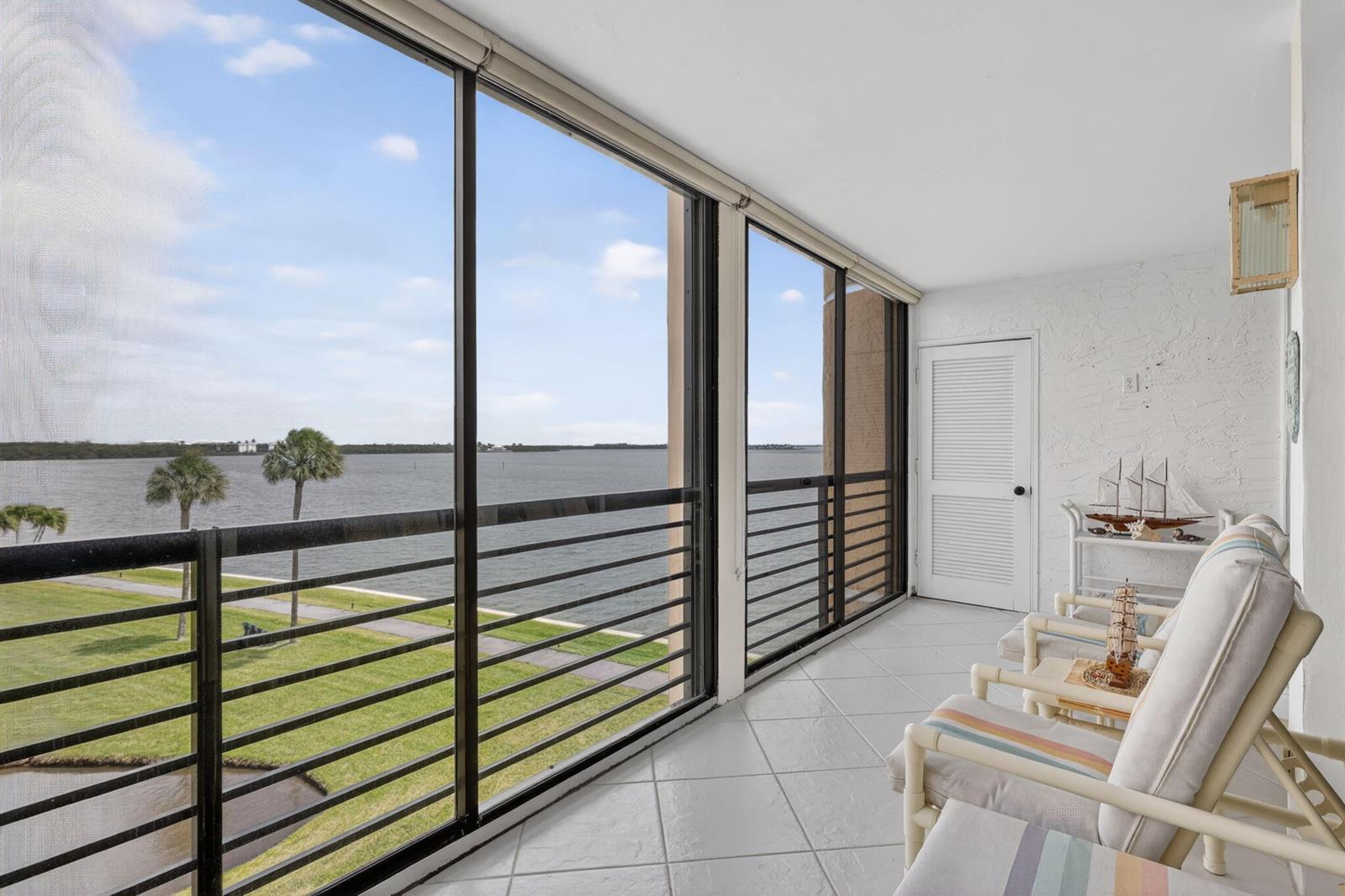 A balcony with tile flooring, white walls, and a view of a grassy lawn and water — 3382 NE Causeway Boulevard # 403, Jensen Beach FL 34957, JENSEN BEACH, FL