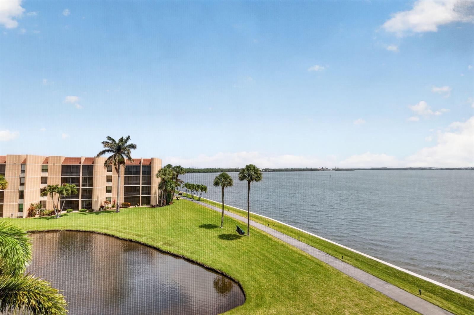 An exterior view of a multi-story building next to a pond and a large lake — 3382 NE Causeway Boulevard # 403, Jensen Beach FL 34957, JENSEN BEACH, FL
