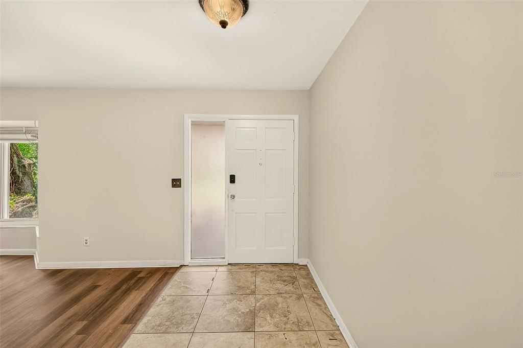 An entryway features a white front door with a sidelight, tile flooring, and wood-look flooring — 303 SAINT AUGUSTINE AVENUE, TEMPLE TERRACE, FL