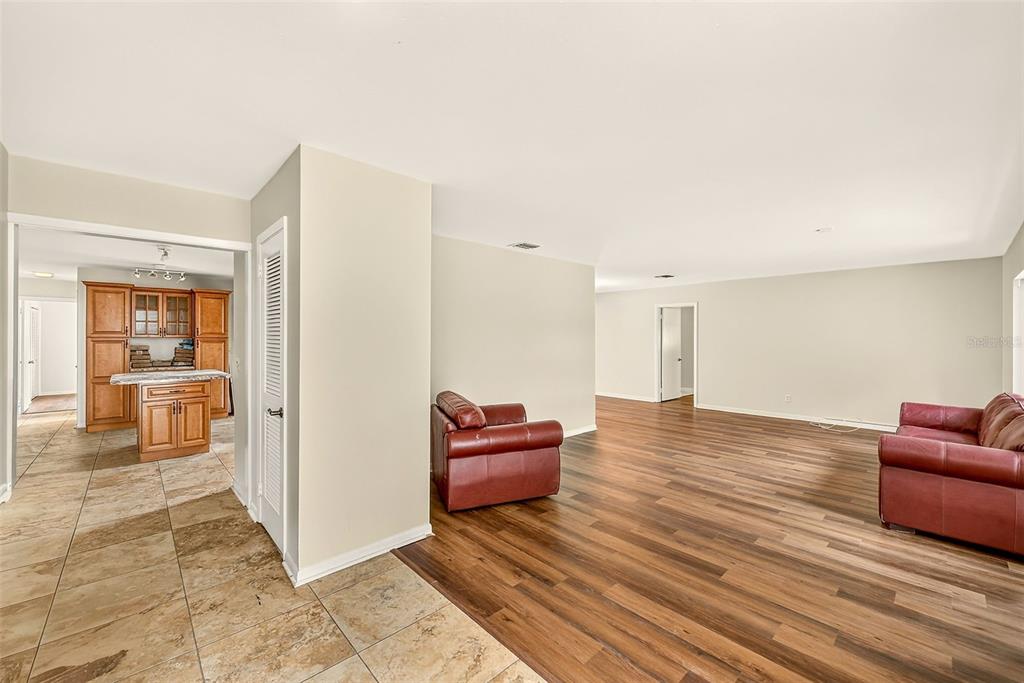 A living room with wood-look flooring and red leather furniture, adjacent to a tiled kitchen — 303 SAINT AUGUSTINE AVENUE, TEMPLE TERRACE, FL