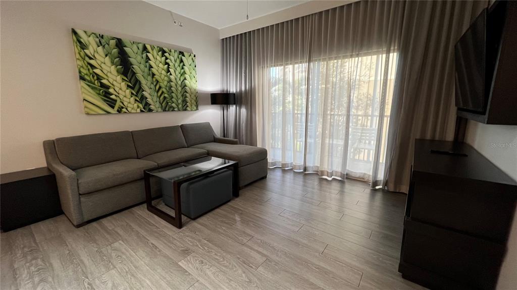 A living room features a gray sectional sofa, a glass coffee table, and floor-to-ceiling curtains — 14501 GROVE RESORT AVENUE UNIT 2233, WINTER GARDEN, FL