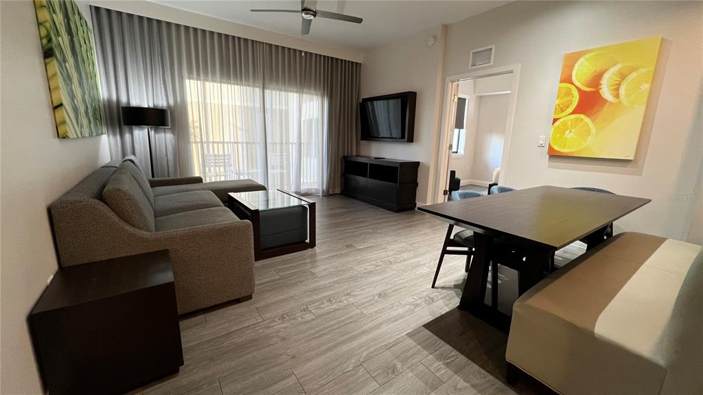 A living and dining area features wood-look flooring, a gray sofa, and a dining table — 14501 GROVE RESORT AVENUE UNIT 2233, WINTER GARDEN, FL