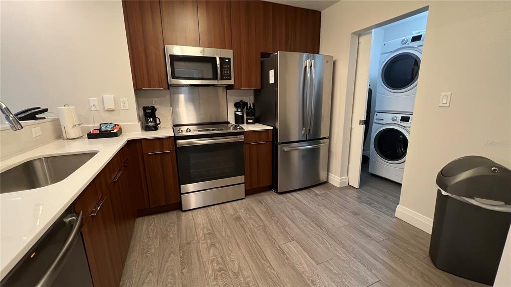 A kitchen features stainless steel appliances, dark wood cabinets, white countertops, and an adjacent laundry — 14501 GROVE RESORT AVENUE UNIT 2233, WINTER GARDEN, FL