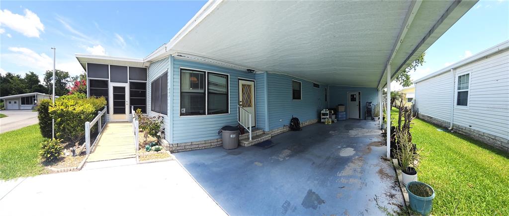 A light blue manufactured home features a covered carport, a ramp, and a screened porch — 245 RAMSGATE WAY, HAINES CITY, FL