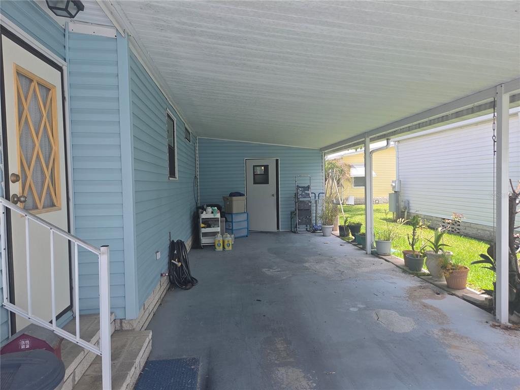 A covered carport with blue siding, a concrete floor, and several potted plants — 245 RAMSGATE WAY, HAINES CITY, FL