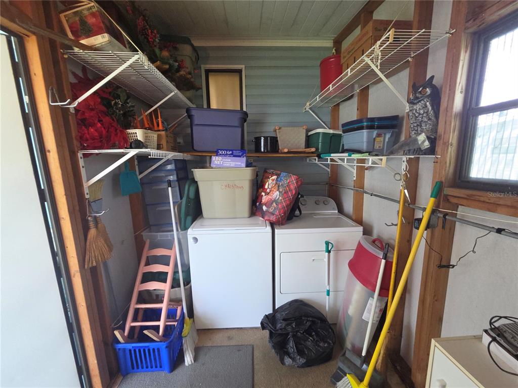 A laundry room contains a washer, dryer, storage shelves, and various household items — 245 RAMSGATE WAY, HAINES CITY, FL