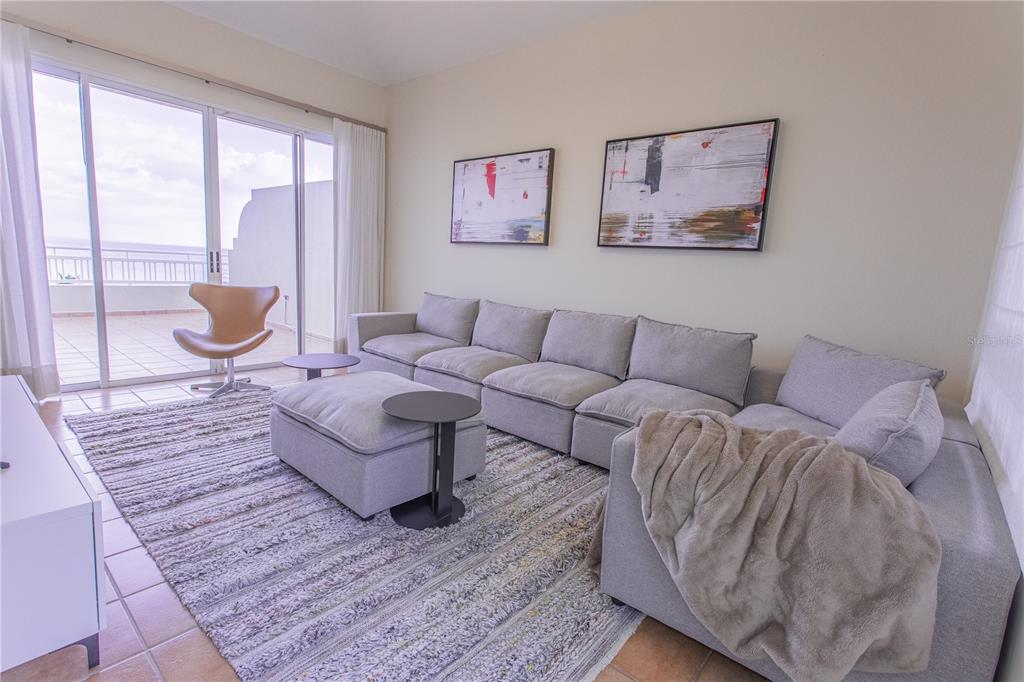 A living room features a large gray sectional sofa, a matching ottoman, and ocean views — 115 CARRETERA 115, KM. 5.8 UNIT 603-A, ANASCO, PR