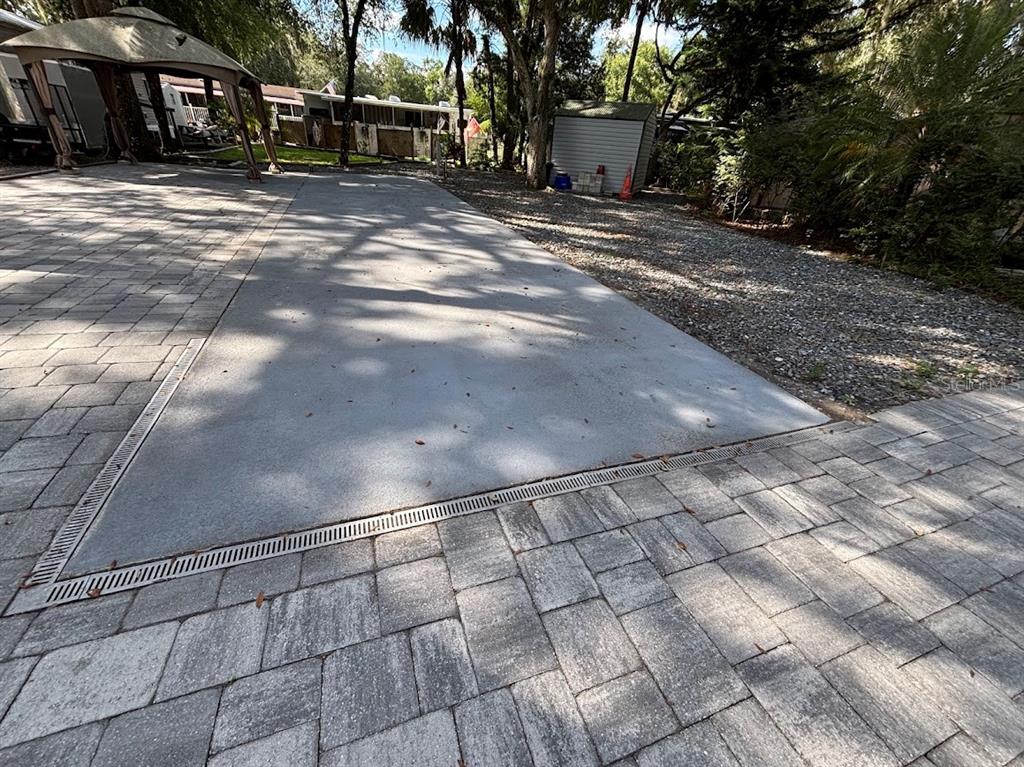A concrete driveway section is bordered by stone pavers and includes a linear drainage grate — 25314 NE 141ST STREET UNIT 377, SALT SPRINGS, FL