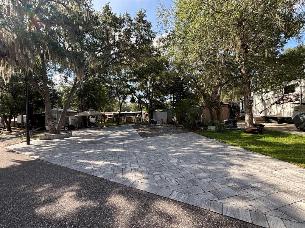 A paved driveway leads to a shaded lot with trees and a small storage shed — 25314 NE 141ST STREET UNIT 377, SALT SPRINGS, FL