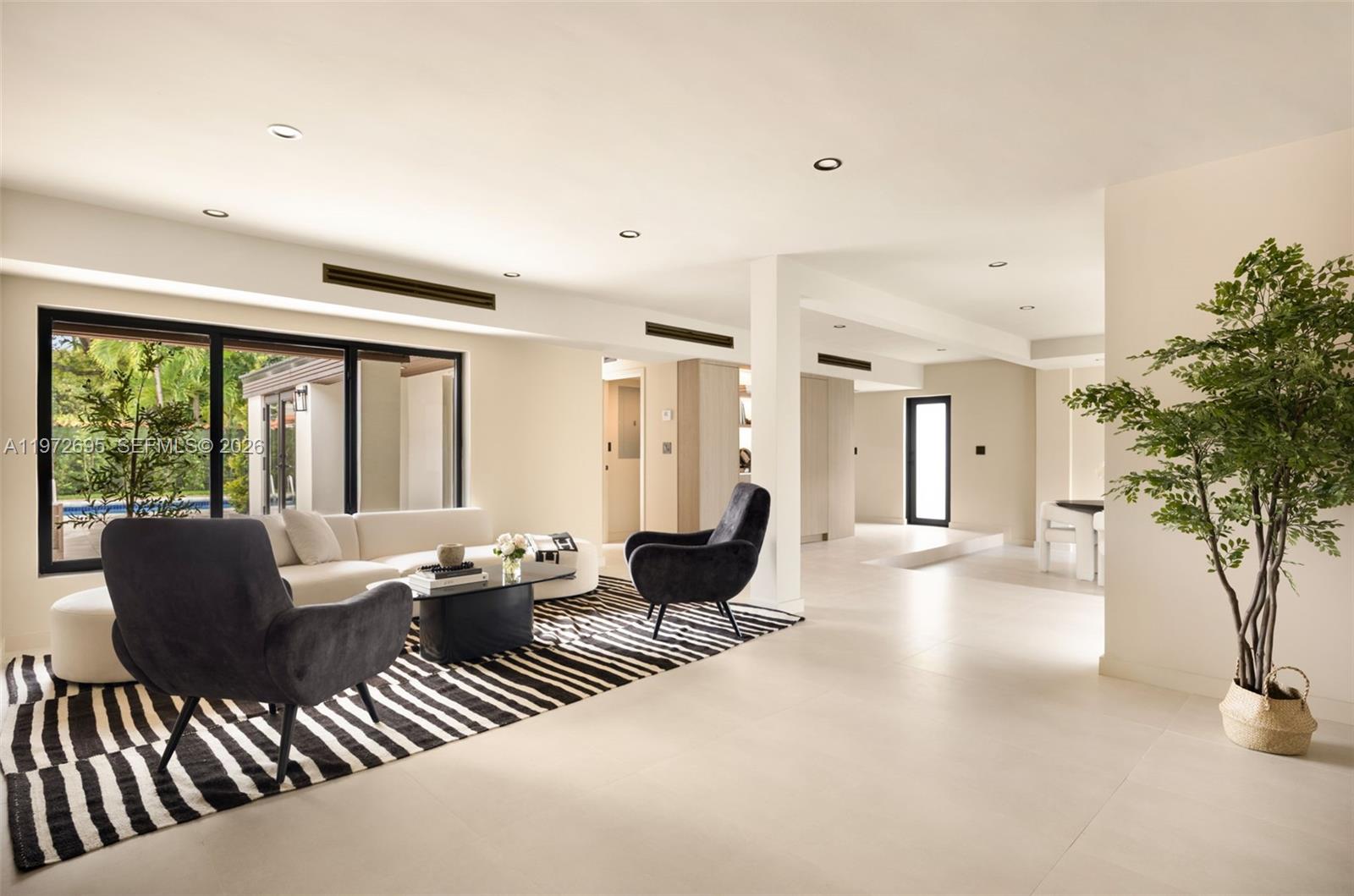 A modern living and dining area features a dark armchair, striped rug, and neutral finishes — 2805 SW 4th Ave, Miami FL 33129, MIAMI, FL