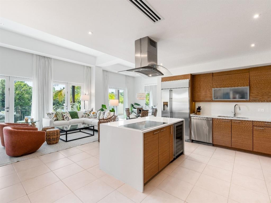 An open-concept kitchen and living area features wood cabinetry, a white island, and tile flooring — Bahia Beach Golf Club LAS VERANDAS CONDOMINIUM UNIT PH 4333, RIO GRANDE, PR