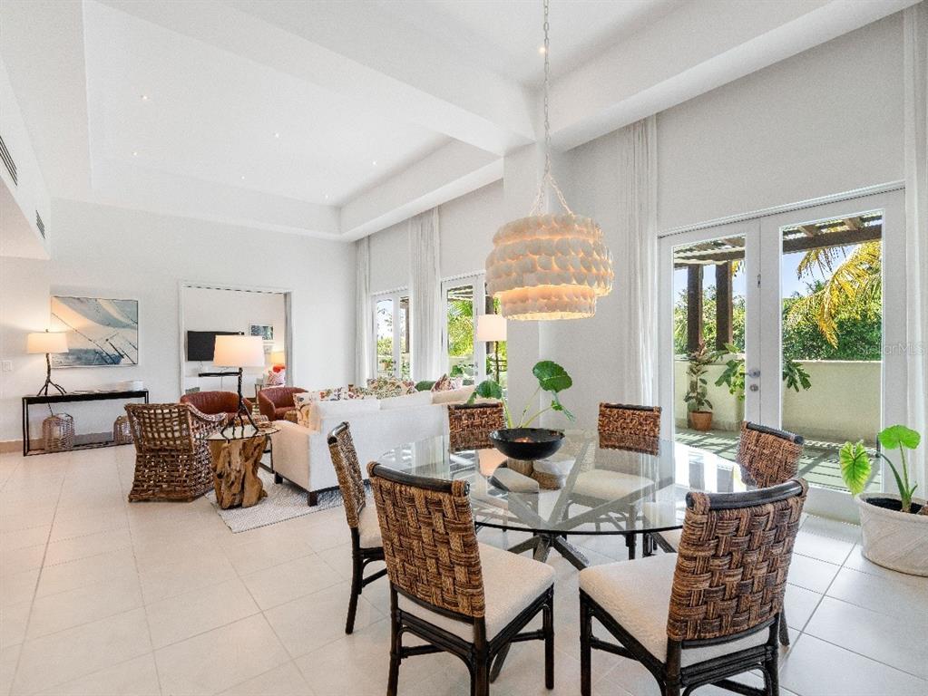 A dining area with a glass table and woven chairs sits beside a bright living room — Bahia Beach Golf Club LAS VERANDAS CONDOMINIUM UNIT PH 4333, RIO GRANDE, PR