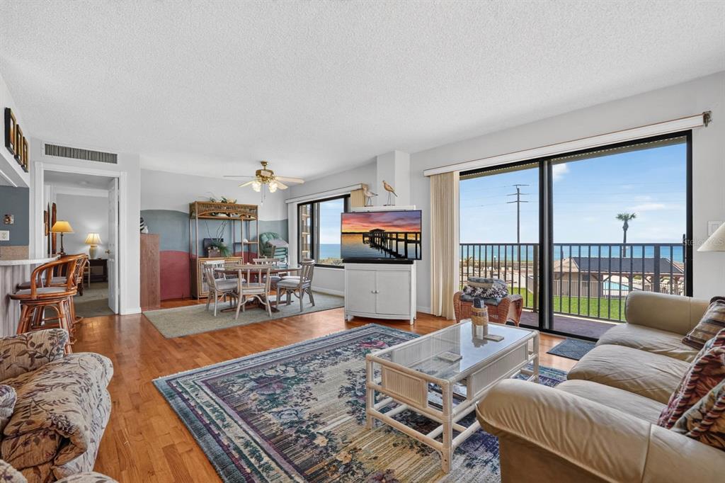 A living and dining area with hardwood floors, a balcony, and ocean views — 3600 S OCEAN SHORE BOULEVARD UNIT 219, FLAGLER BEACH, FL