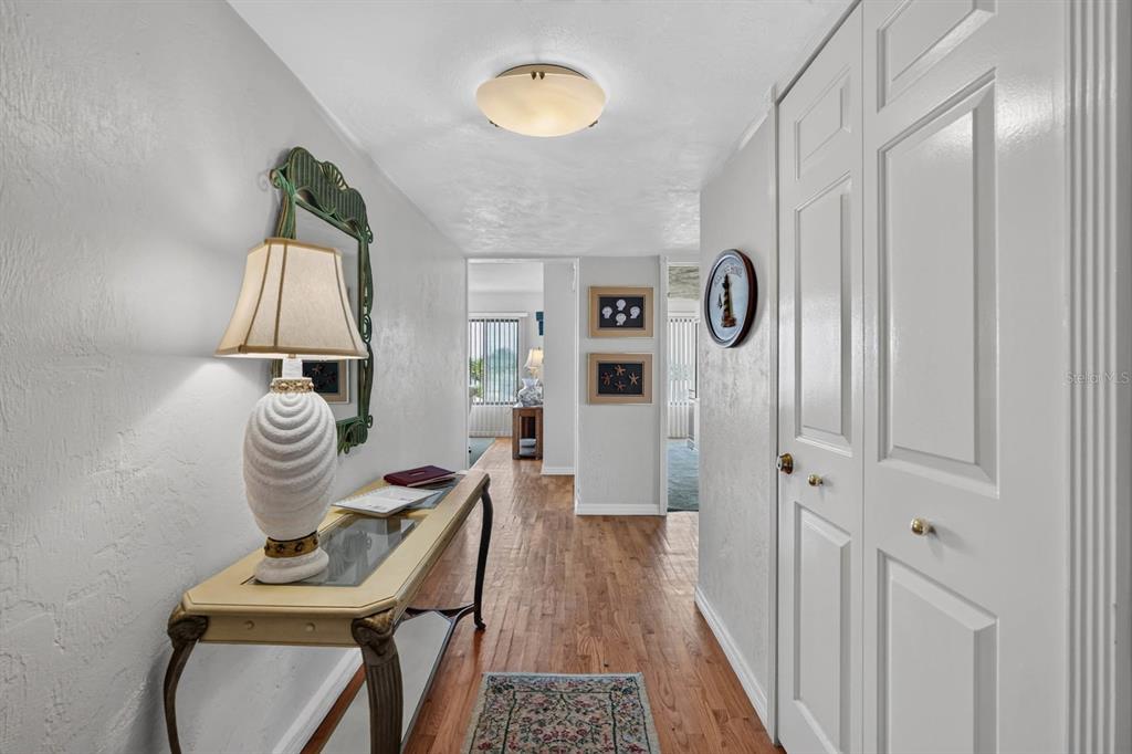 A hallway features hardwood floors, a console table with a lamp, and white paneled doors — 3600 S OCEAN SHORE BOULEVARD UNIT 219, FLAGLER BEACH, FL