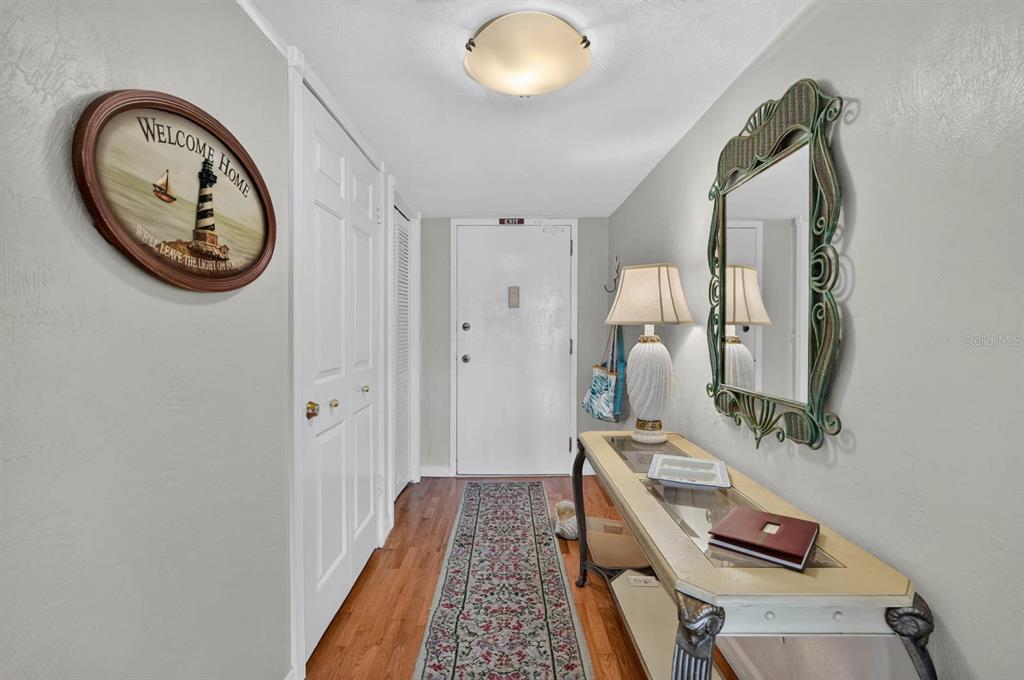 An entryway features a console table, a decorative mirror, a runner rug, and a door — 3600 S OCEAN SHORE BOULEVARD UNIT 219, FLAGLER BEACH, FL