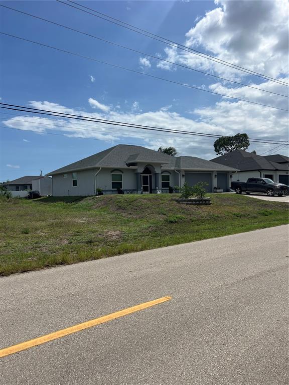 A single-story house with a gray exterior, a multi-car garage, and a sloped front yard — 406 JACARANDA PKWY E, CAPE CORAL, FL