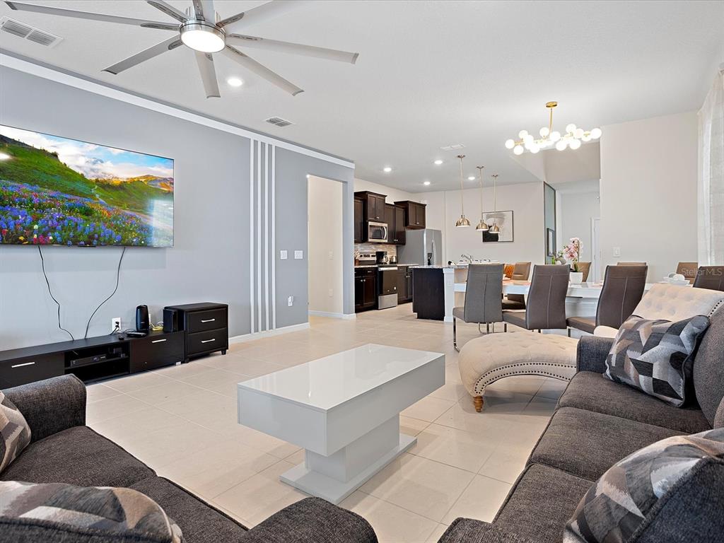 A living room with gray sofas, a white coffee table, and an open-concept kitchen — 3835 LANA AVENUE, DAVENPORT, FL