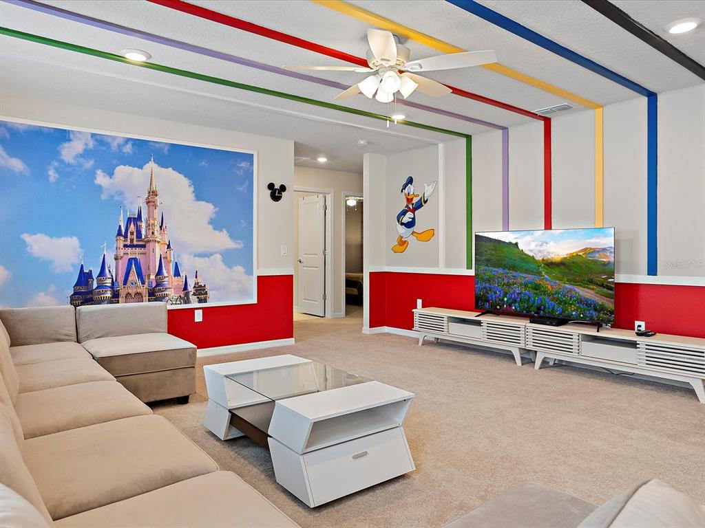 A Disney-themed living room features a castle mural, Donald Duck decal, and colorful ceiling stripes — 3835 LANA AVENUE, DAVENPORT, FL