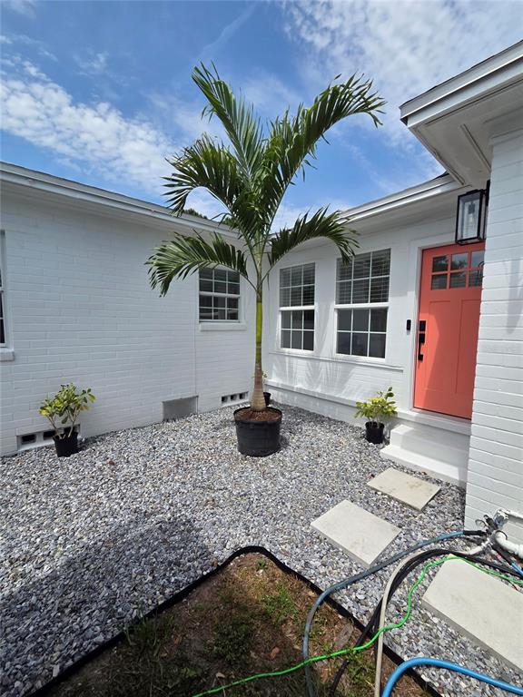 A white brick house exterior features a coral front door and a potted palm tree — 4016 9TH AVENUE N, ST PETERSBURG, FL