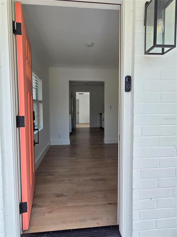 An open coral-colored front door reveals a hallway with light wood flooring and white walls — 4016 9TH AVENUE N, ST PETERSBURG, FL
