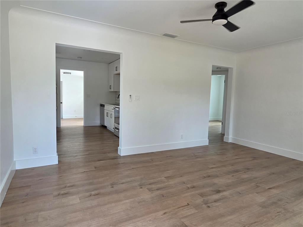 A living area with wood-look flooring leads to a kitchen and a hallway — 4016 9TH AVENUE N, ST PETERSBURG, FL