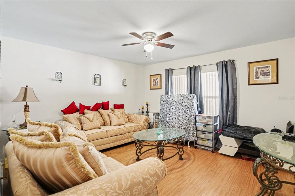 A living room features beige patterned sofas, a glass coffee table, and wood-look flooring — 720 VALRICO HILLS LANE, VALRICO, FL