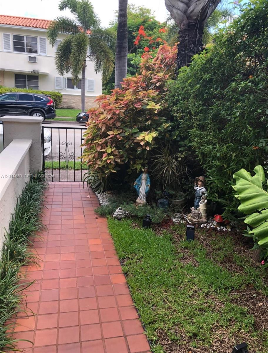 A tiled walkway leads to a gated entrance with garden statues and lush landscaping — 248 Majorca Ave # 248, Coral Gables FL 33134, CORAL GABLES, FL
