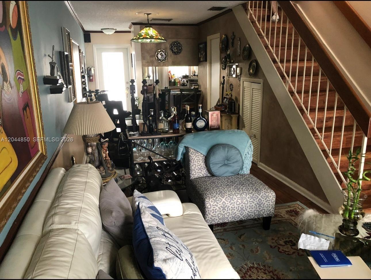 A living room features a white sofa, a patterned armchair, and a staircase with railings — 248 Majorca Ave # 248, Coral Gables FL 33134, CORAL GABLES, FL