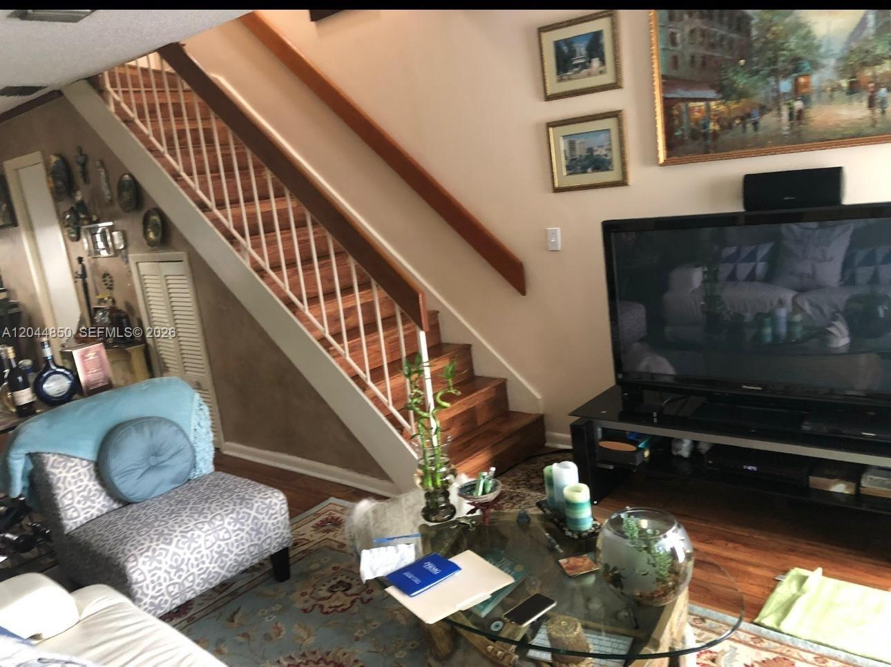 A living room features a wooden staircase, a glass coffee table, and a television console — 248 Majorca Ave # 248, Coral Gables FL 33134, CORAL GABLES, FL
