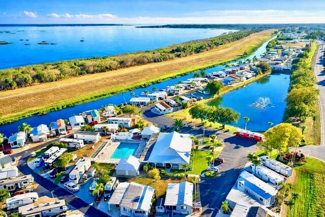 This aerial view shows a waterfront mobile home community with a pool and clubhouse — 7950 W Hwy 78 Highway, Okeechobee FL 34974, OKEECHOBEE, FL