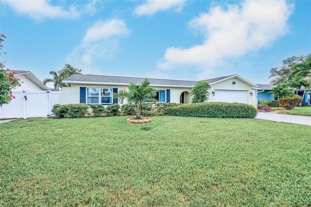 A single-story house with a white garage, blue shutters, and a palm tree in front — 9069 127TH STREET, SEMINOLE, FL