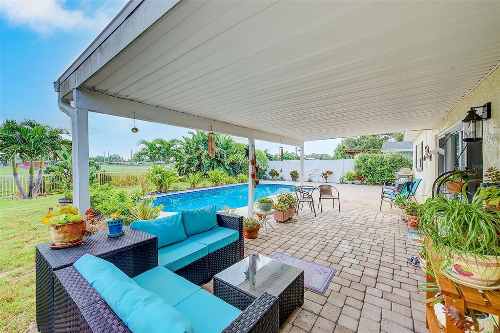 A covered patio with outdoor furniture overlooks a swimming pool and a grassy backyard — 9069 127TH STREET, SEMINOLE, FL
