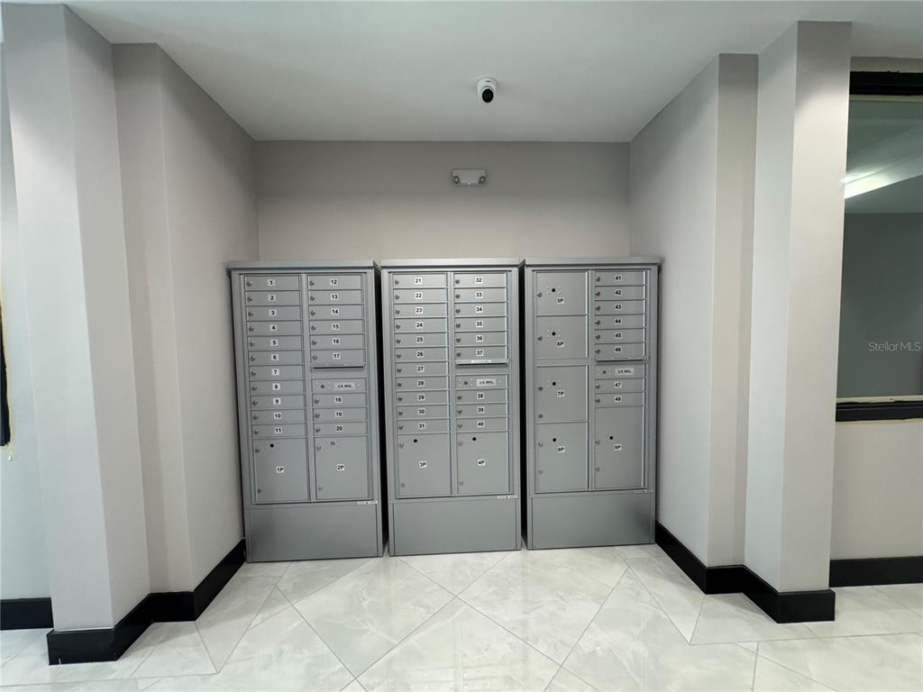 A mailroom features three sets of gray metal mailboxes against a light gray wall — 13564 VILLAGE PARK DRIVE UNIT 310, ORLANDO, FL