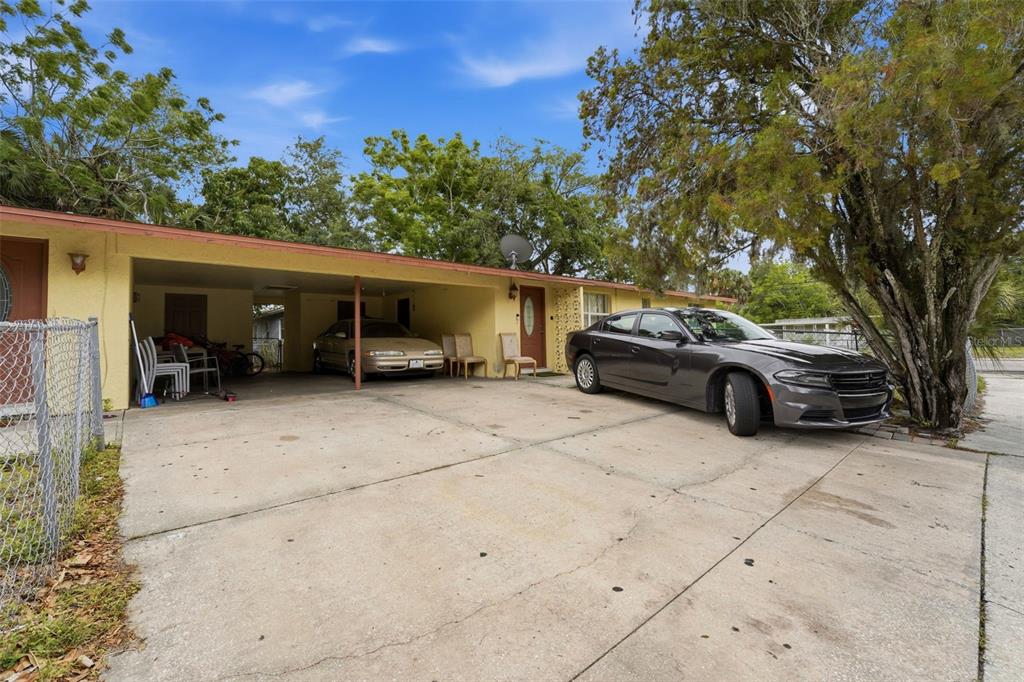 A yellow house features a concrete driveway, a covered carport, and a parked gray sedan — 1610 22ND STREET, SARASOTA, FL