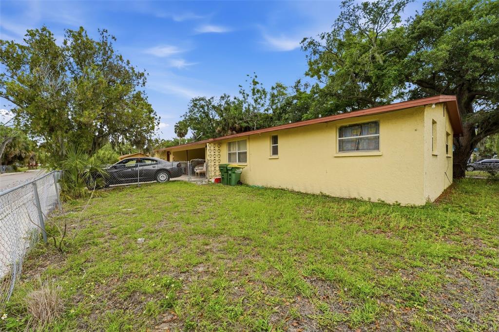 A yellow single-story house with a carport and a chain-link fence in the yard — 1610 22ND STREET, SARASOTA, FL