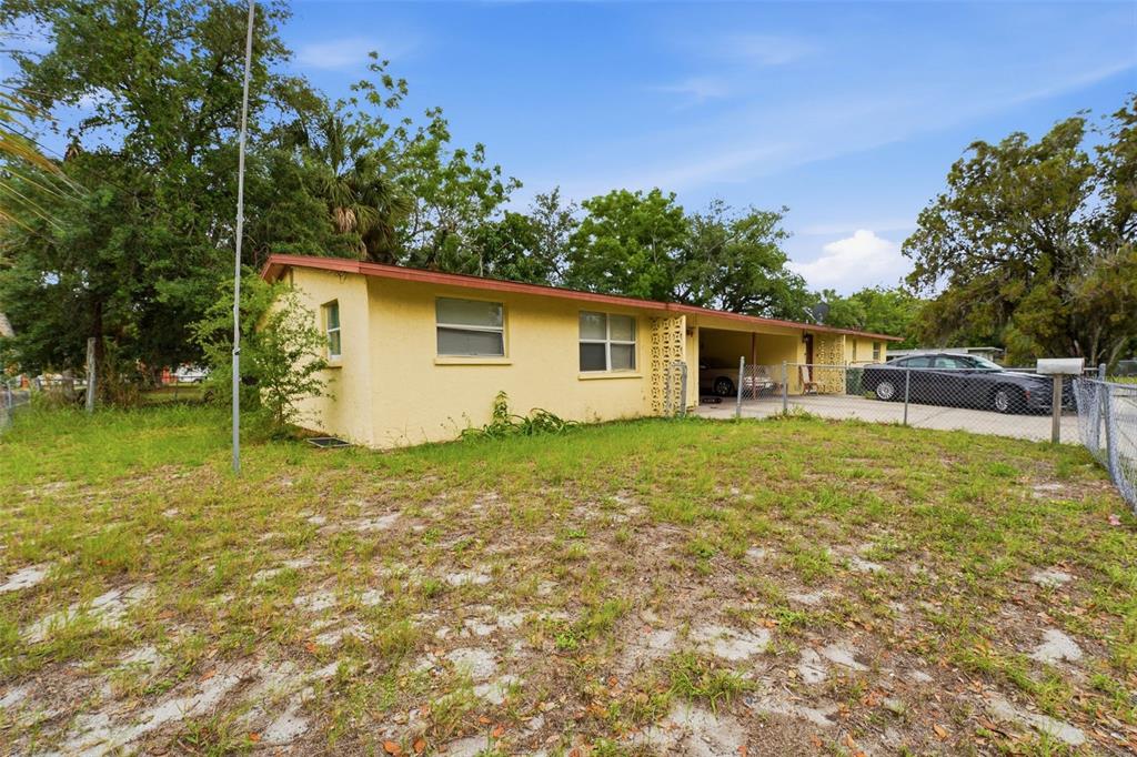 A yellow, single-story house with a carport and a chain-link fence in the yard — 1610 22ND STREET, SARASOTA, FL